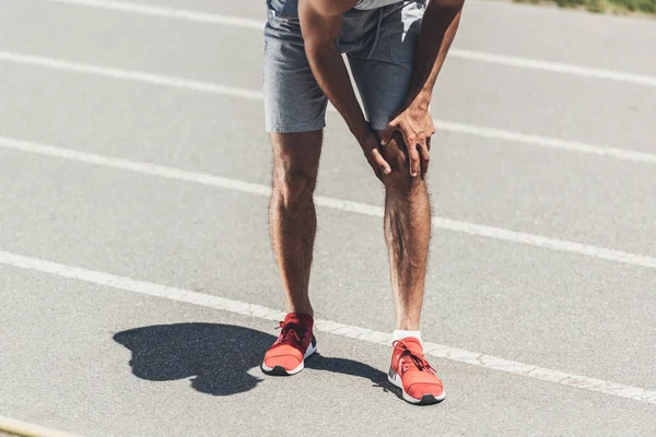 Cropped shot of runner with knee injury on running track — Stock Photo