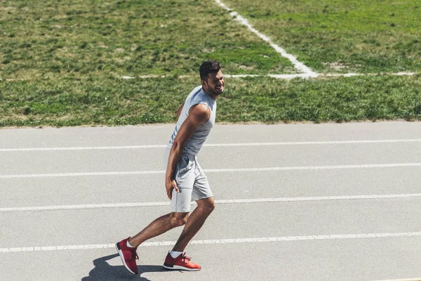 Sofrendo jovem corredor receber lesão na perna durante a corrida — Fotografia de Stock