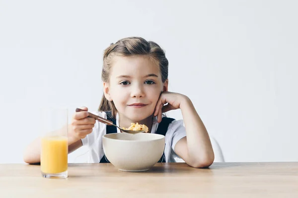 Smiling little schoolgirl eating healthy breakfast isolated on white — Stock Photo