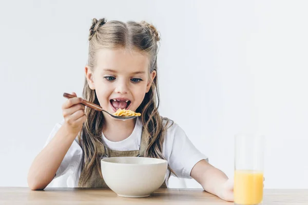 Збуджена маленька школярка їсть здоровий сніданок ізольовано на білому — стокове фото