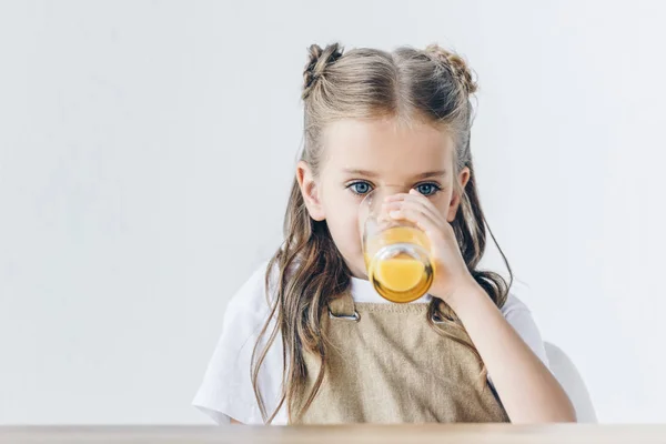 Beautiful little schoolgirl with drinking orange juice isolated on white — Stock Photo