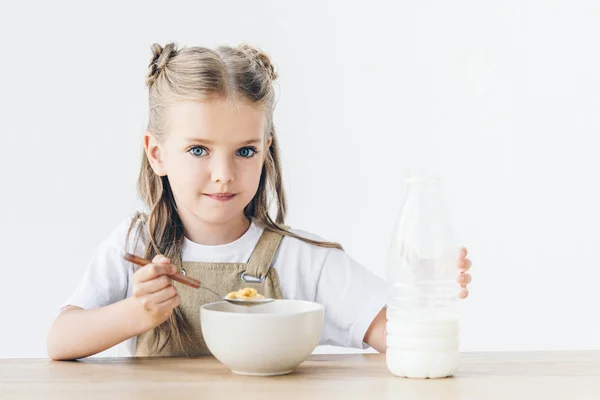 Adorável colegial comendo cereal com leite para café da manhã isolado em branco — Fotografia de Stock