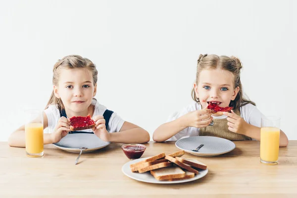 Kleine Schwestern essen Toasts mit Marmelade zum Frühstück isoliert auf weiß — Stockfoto