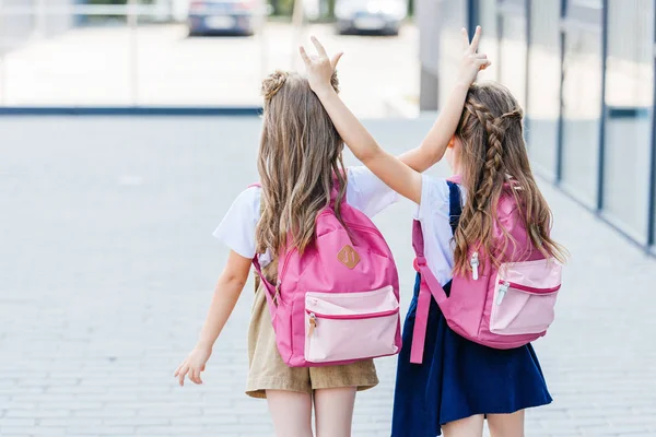 Вид ззаду маленькі школярки роблять жест рогів один одному на вулиці — Stock Photo
