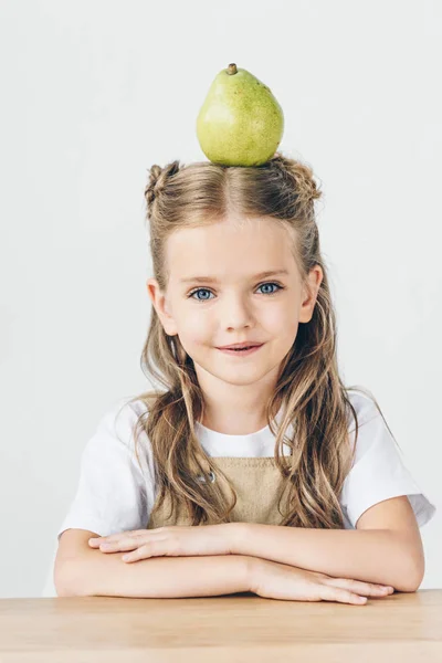 Счастливая маленькая школьница с спелыми грушами на голове изолированы на белом — стоковое фото