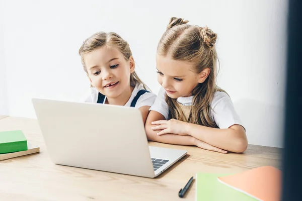 Glückliche kleine Schulmädchen mit Laptop zum Lernen isoliert auf weiß — Stockfoto