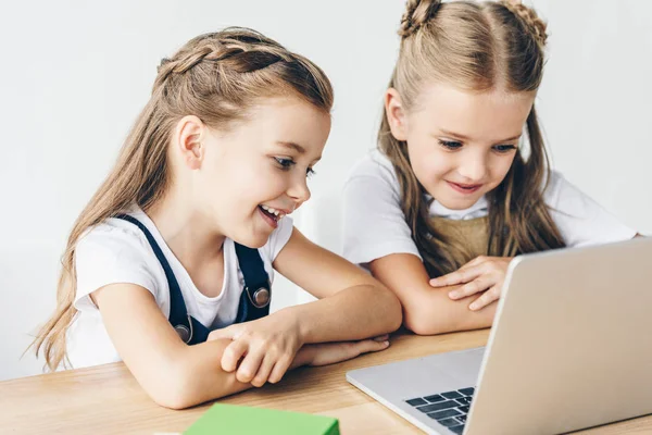 Lächeln kleine Schulmädchen mit Laptop für das Lernen isoliert auf weiß — Stockfoto