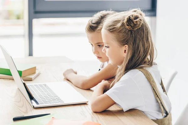 Маленькі школярки використовують ноутбук для вивчення ізольовані на білому — стокове фото