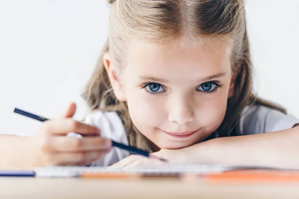 Portrait en gros plan de la petite écolière dessinant avec des crayons de couleur et regardant la caméra isolée sur blanc — Photo de stock