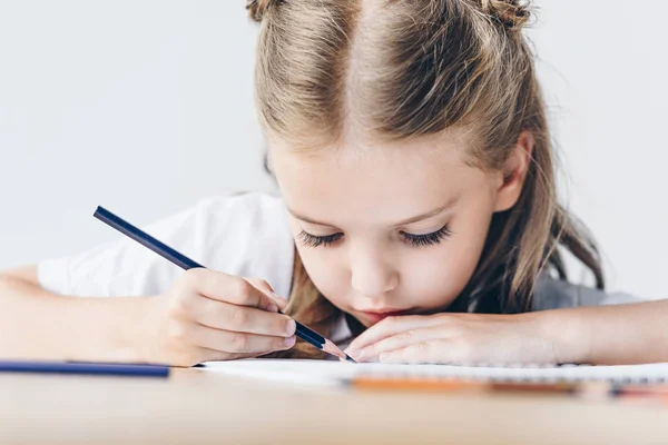 Nahaufnahme einer fokussierten kleinen Schülerin, die mit Farbstiften isoliert auf Weiß zeichnet — Stockfoto