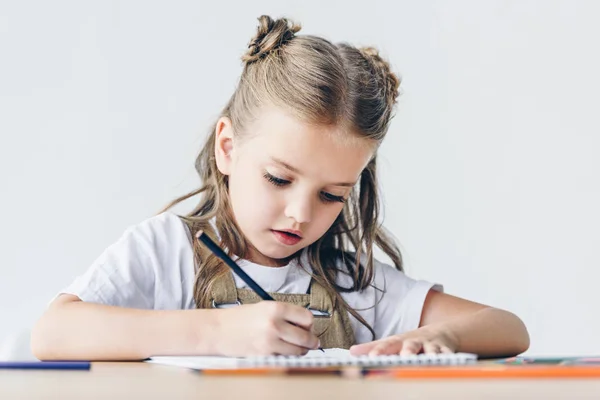 Little schoolgirl drawing with color pencils isolated on white — Stock Photo