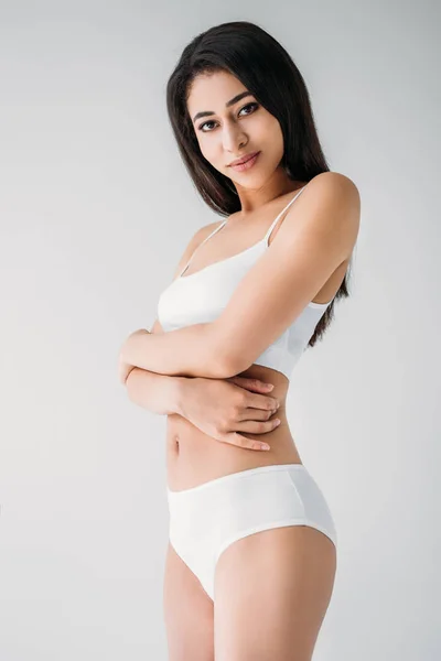 Attractive mixed race woman in white lingerie with crossed hands isolated on gray background — Stock Photo