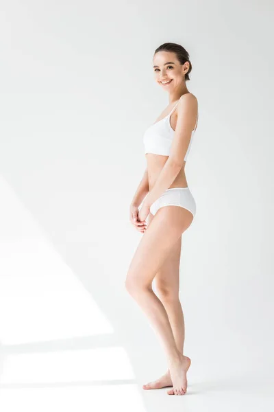Sorrindo atraente mulher caucasiana em lingerie branca no fundo cinza — Fotografia de Stock