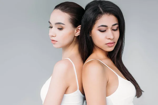 Attractive multicultural women standing back to back isolated on gray background — Stock Photo