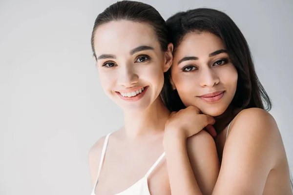 Portrait of smiling multicultural women looking at camera isolated on gray background — Stock Photo
