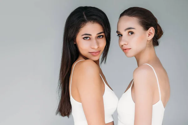 Portrait of multicultural women looking at camera isolated on gray background — Stock Photo