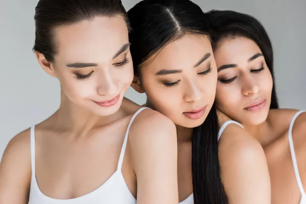 Young smiling multiethnic women posing isolated on gray background — Stock Photo