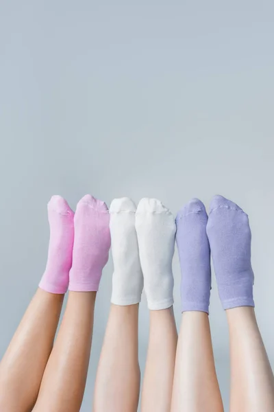 Vista parcial de las piernas femeninas en diferentes calcetines de colores aislados sobre fondo gris — Stock Photo