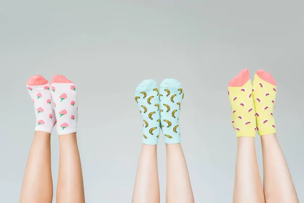 Image recadrée de jambes féminines dans différentes chaussettes colorées isolées sur fond gris — Photo de stock