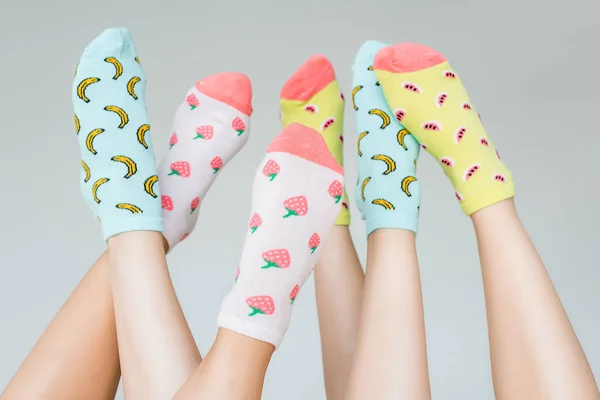 Vista parziale di piedi femminili in calzini fruttati colorati, isolati su grigio — Foto stock