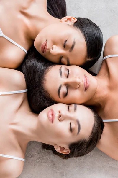 Top view of charming female multiethnic friendship lying with closed eyes — Stock Photo