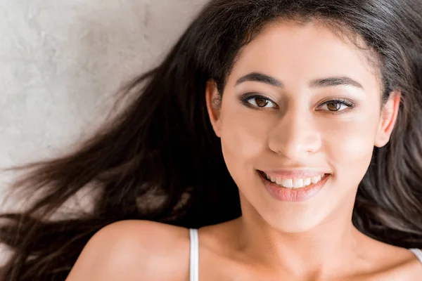 Bela sorrindo menina de raça mista olhando para a câmera, em cinza — Fotografia de Stock