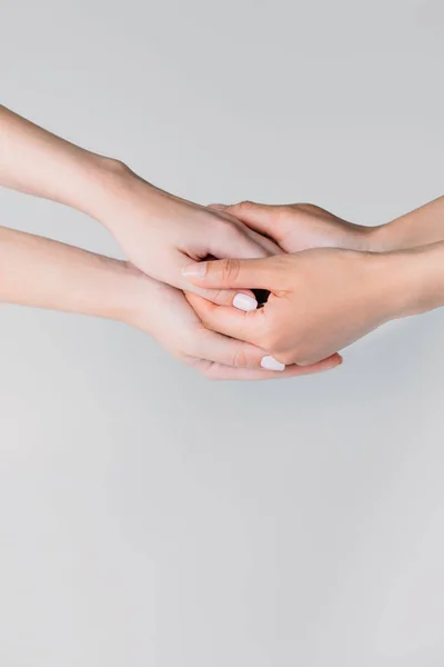 Vista parcial de las niñas cogidas de la mano, aisladas en gris - foto de stock