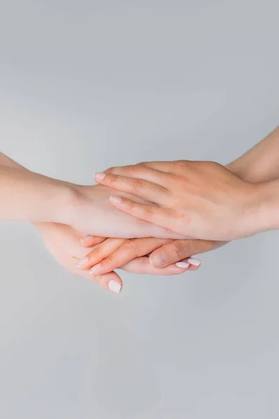 Vista ritagliata di ragazze tenere le mani insieme, isolato su grigio — Foto stock
