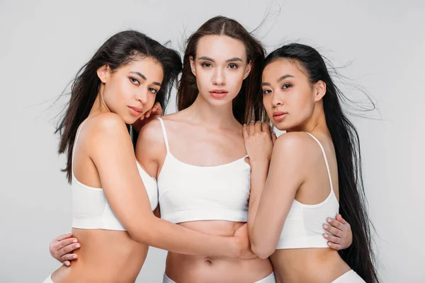 Beautiful multicultural women posing in white bra, isolated on grey — Stock Photo