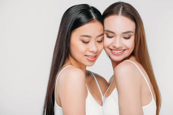 Asian and caucasian smiling girls in white bra, isolated on grey — Stock Photo