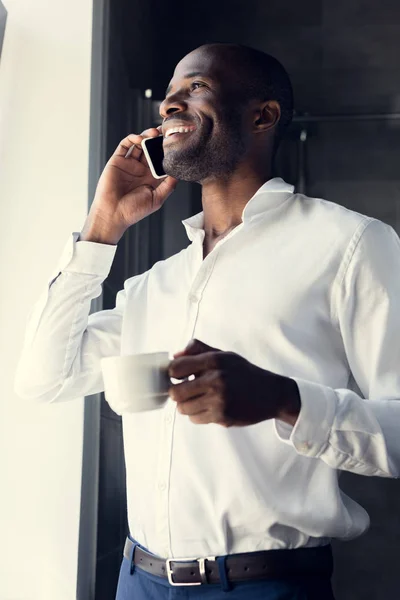Blick von unten auf den hübschen jungen Geschäftsmann im weißen Hemd, der in der Kaffeepause telefoniert — Stockfoto