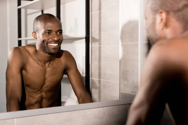 Felice giovane uomo guardando specchio in bagno — Foto stock