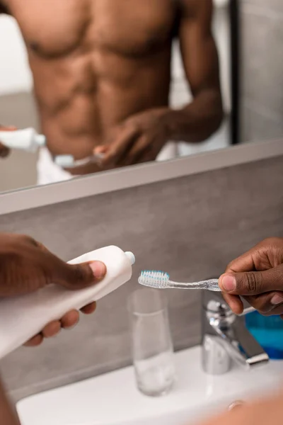 Plan recadré de l'homme appliquant du dentifrice sur la brosse devant le miroir — Photo de stock