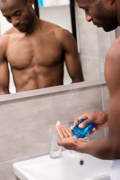 Schöner junger Mann gießt nach Rasierwasser auf die Hand — Stockfoto