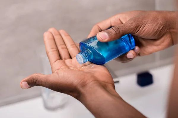 Abgeschnittener Schuss eines Mannes, der nach Rasierwasser auf die Hand gießt — Stockfoto