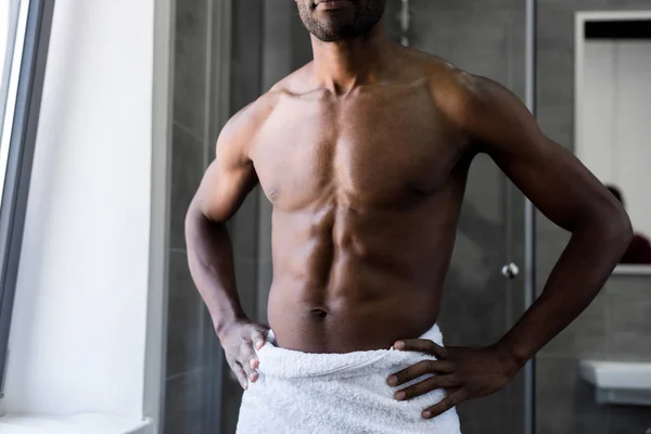 Cropped shot of handsome bare-chested african american man in towel standing with hands on waist in bathroom — Stock Photo