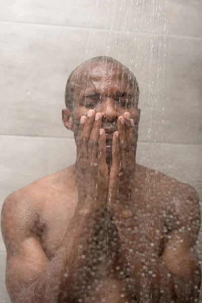 Guapo africano americano hombre lavado cuerpo en ducha - foto de stock