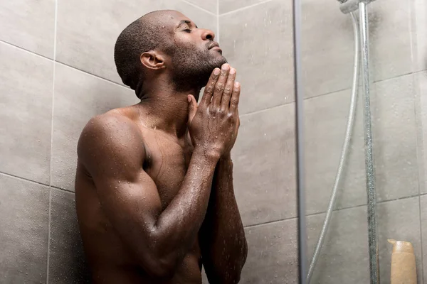 Handsome african american man with closed eyes taking shower — Stock Photo