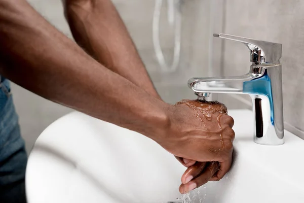 Частичный вид на Африканский американец стирает в ванной комнате — стоковое фото