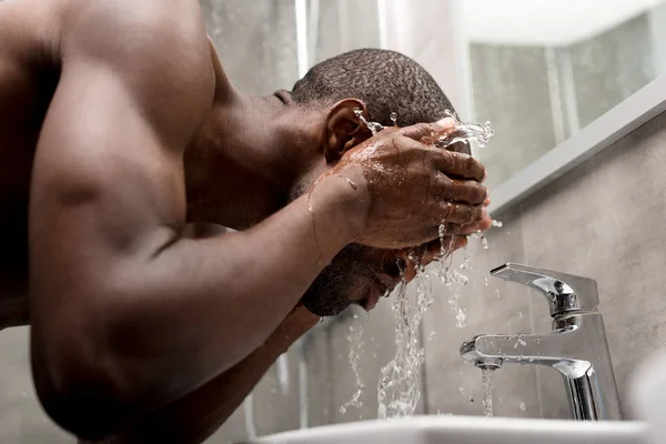 Vista lateral de bonito nu-peito afro-americano homem lavando no banheiro — Fotografia de Stock