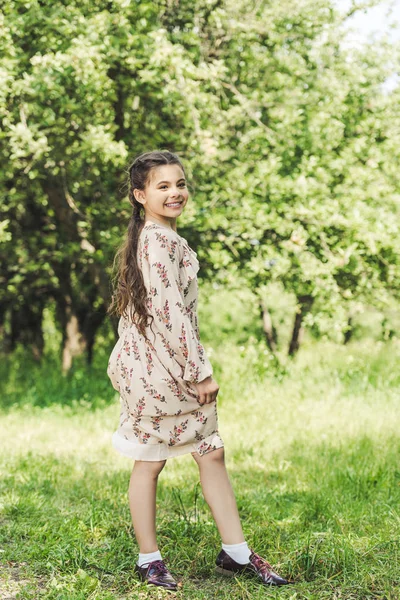 Glückliches Kind in stylischem Kleid posiert im Sommerpark — Stockfoto