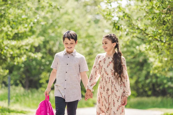 Adorables enfants tenant la main et marchant par le parc — Photo de stock