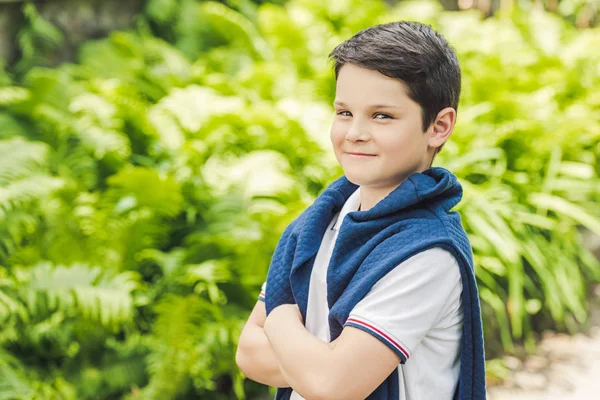 Niño con estilo con puente sobre los hombros mirando a la cámara con los brazos cruzados - foto de stock