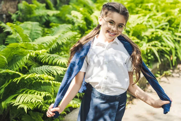 Glückliches Schulmädchen in weißem Hemd und Pullover über den Schultern — Stockfoto