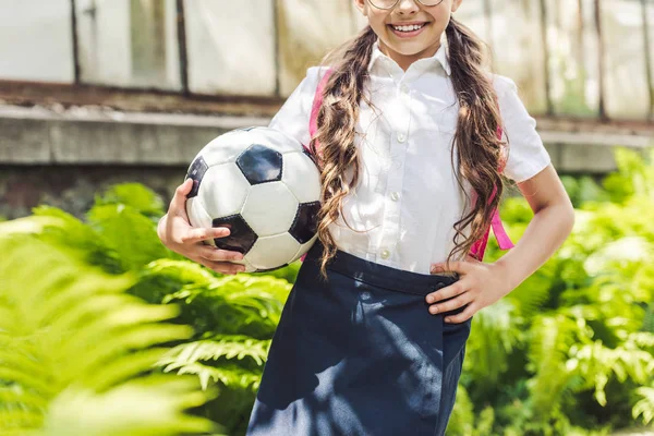 Обрезанный снимок школьницы с футбольным мячом в саду — стоковое фото