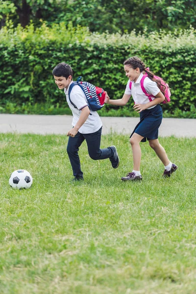 Active schoolchildren playing soccer together on meadow in park — Stock Photo