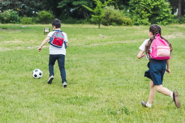 Escolares jogando futebol juntos no prado no parque — Fotografia de Stock