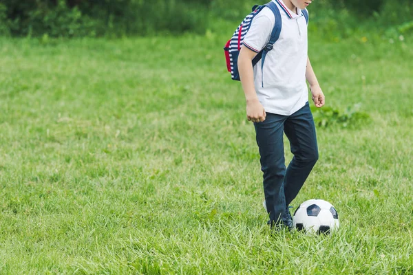 Cropped shot of kid playing with soccer ball on grass field — Stock Photo