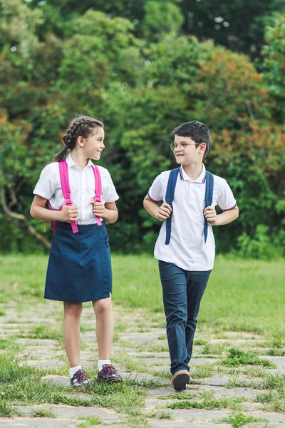 Schoolchildren walking by pathway in park together and chatting — Stock Photo