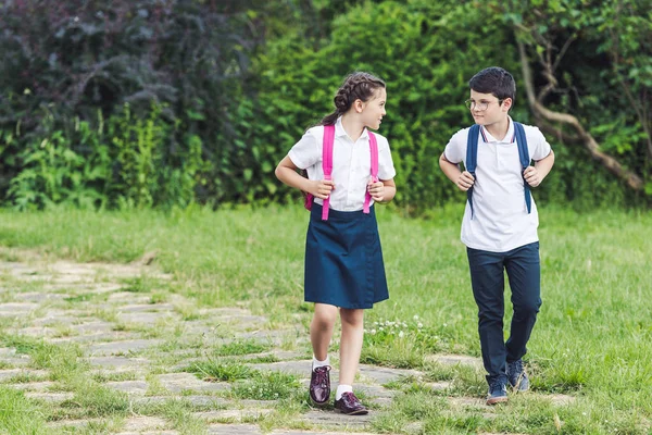 Очаровательные школьники, идущие по тропинке в парке вместе — стоковое фото